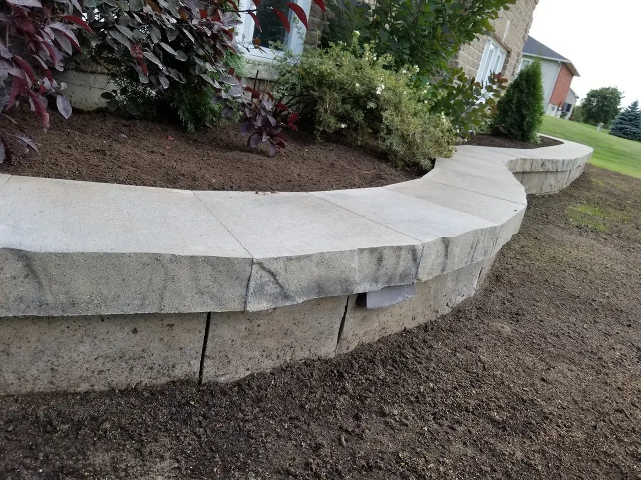Curved stone retaining wall and garden bed in Carleton Place by ALM Construction