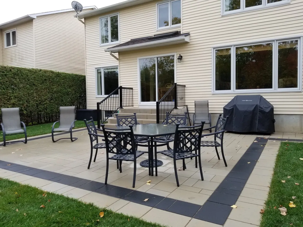 Rectangular paver patio with a dark contrasting border and outdoor dining set in a Kanata backyard, built by ALM